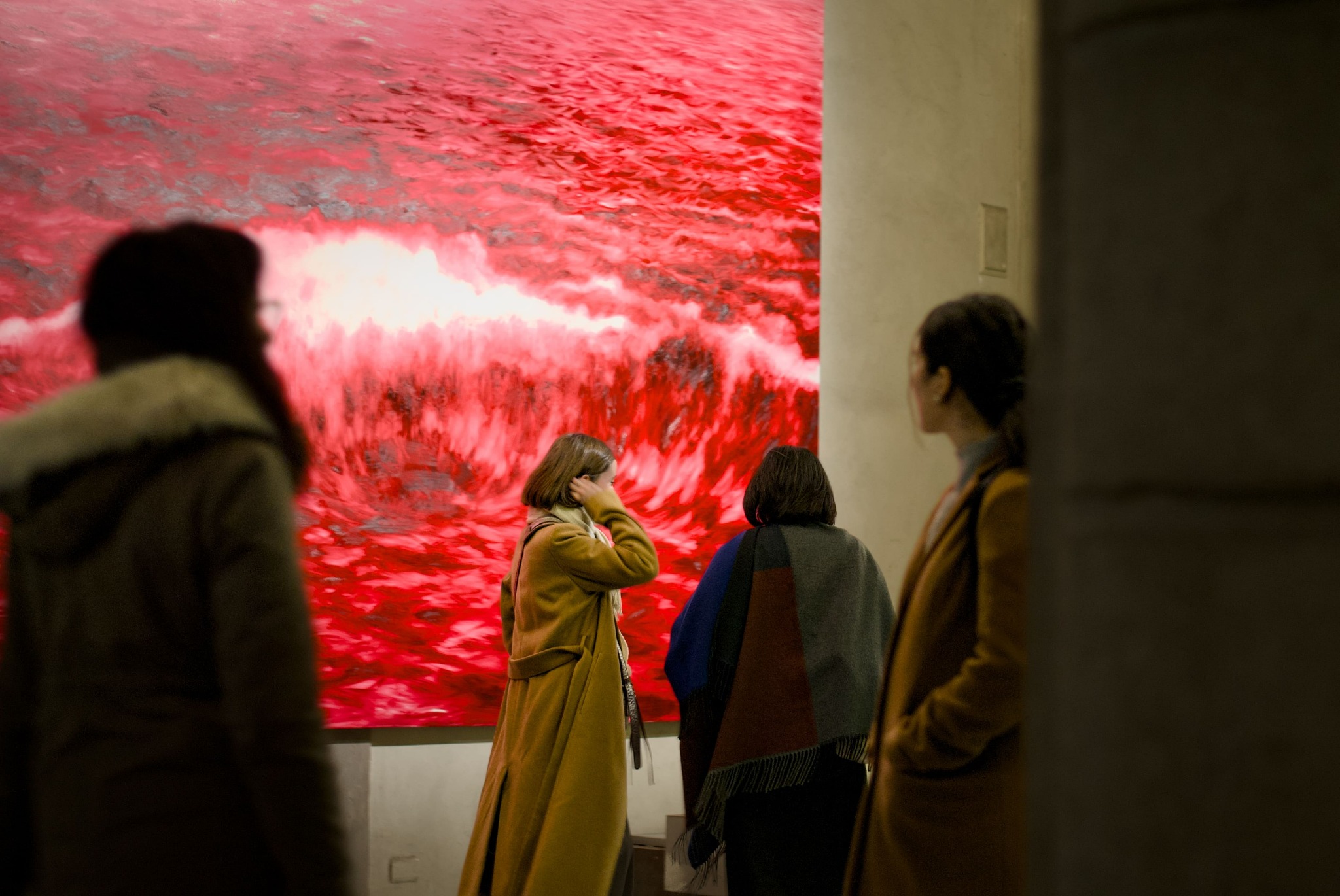 Visitatori davanti a un'opera fotografica rossa in uno spazio espositivo